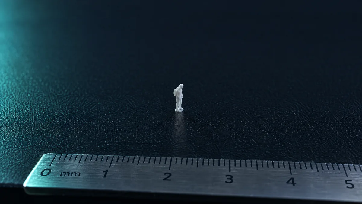 Tiny 3D-printed figure in the middle of an empty printer bed, with a millimetre ruler